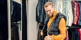 Young man admiring himself looking in a mirror in a menswear shop.